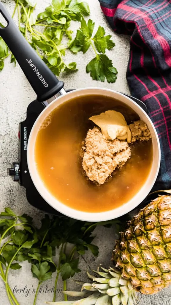 Pineapple juice, brown sugar, and dijon mustard cooking in a pan.