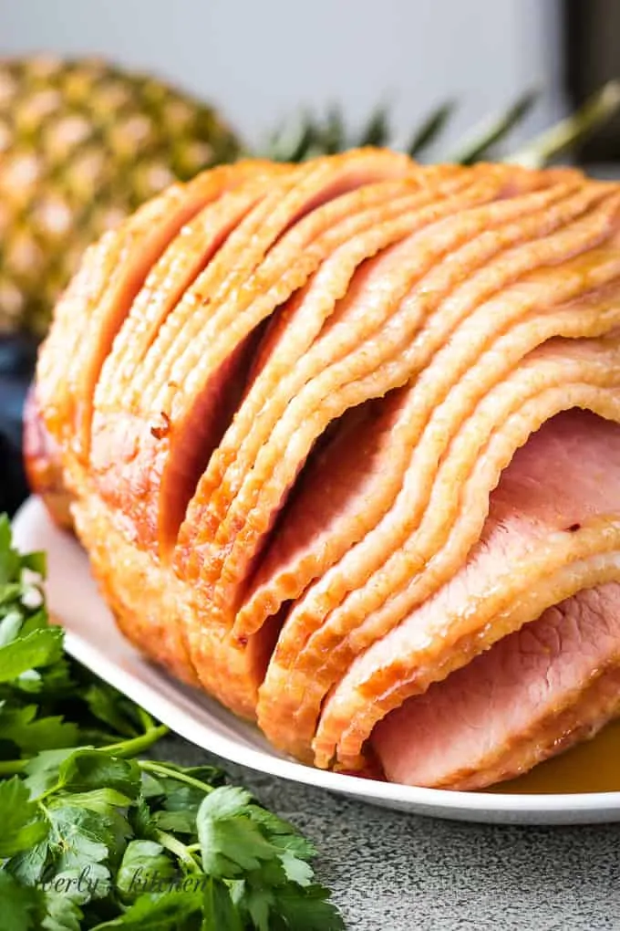 A bone-in oven baked ham on a plate.