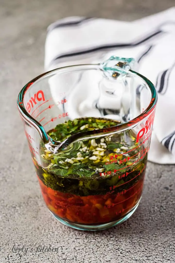 Vinegar, oil, and other ingredients in a glass measuring cup.