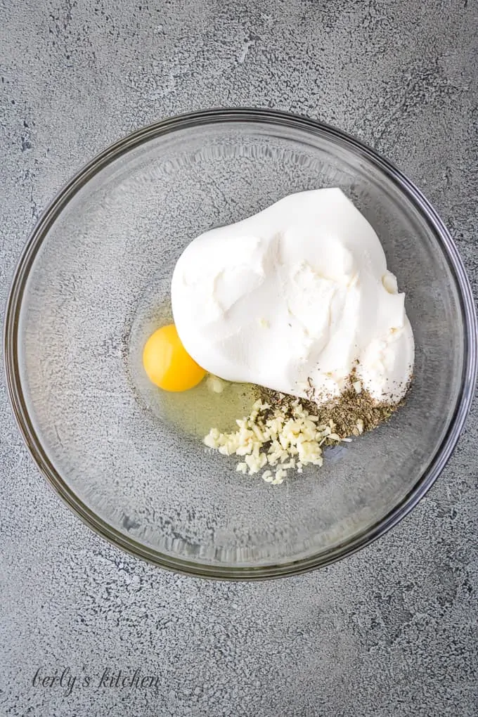 Ricotta cheese and other ingredients in a large mixing bowl.