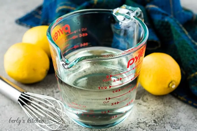 The simple syrup in a measuring cup beside a whisk.