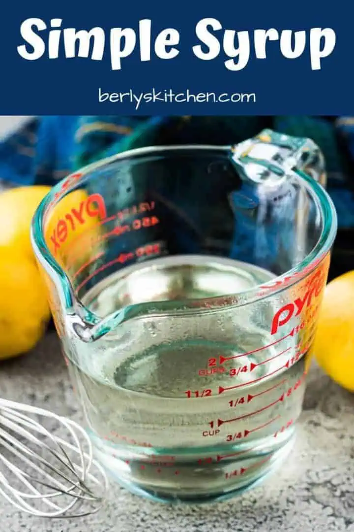 The simple syrup in a cup surrounded by fresh lemons.