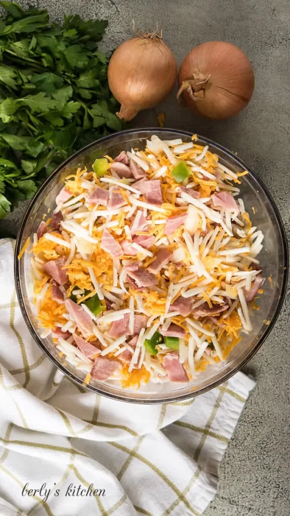 Hash browns, cheese, peppers and other ingredients in a bowl.