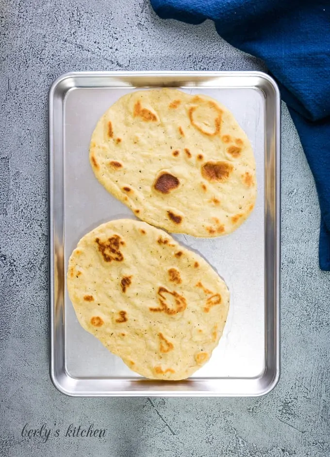 Two large flatbreads on a sheet pan.