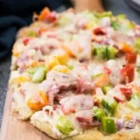 The ham flatbread on a wooden cutting board.