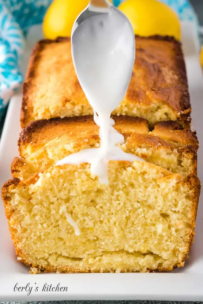 Lemon glaze being drizzled over the bread.