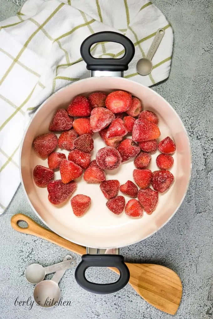 Whole fresh strawberries and sugar in a pot.