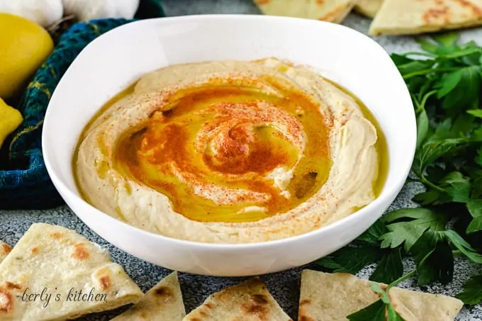 A bowl of hummus surrounded by homemade flatbread.