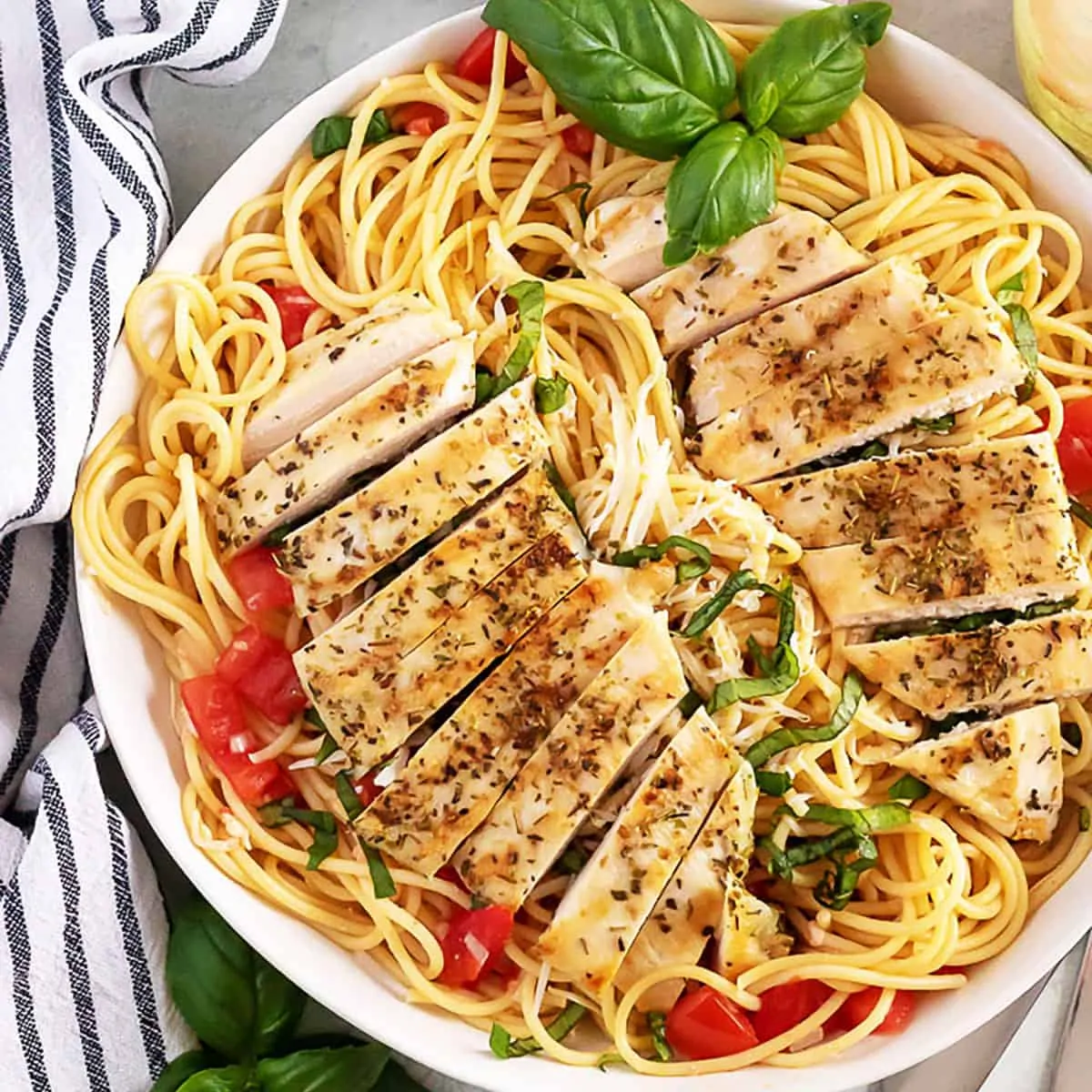 Top down view of sliced chicken on top of bruschetta pasta.