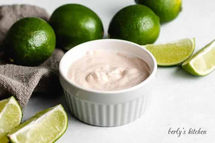 The chipotle cream sauce in a ramekin accented with limes.