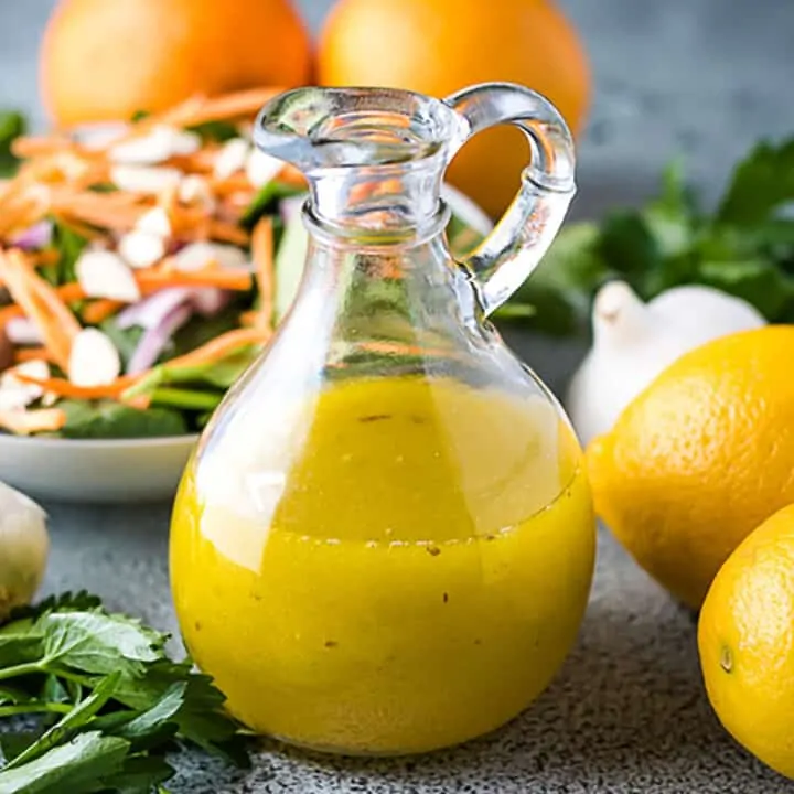 Citrus vinaigrette dressing next to two lemons and garlic.