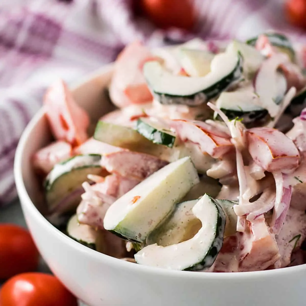 Bowl of chopped cucumbers and tomatoes tossed in ranch dressing.