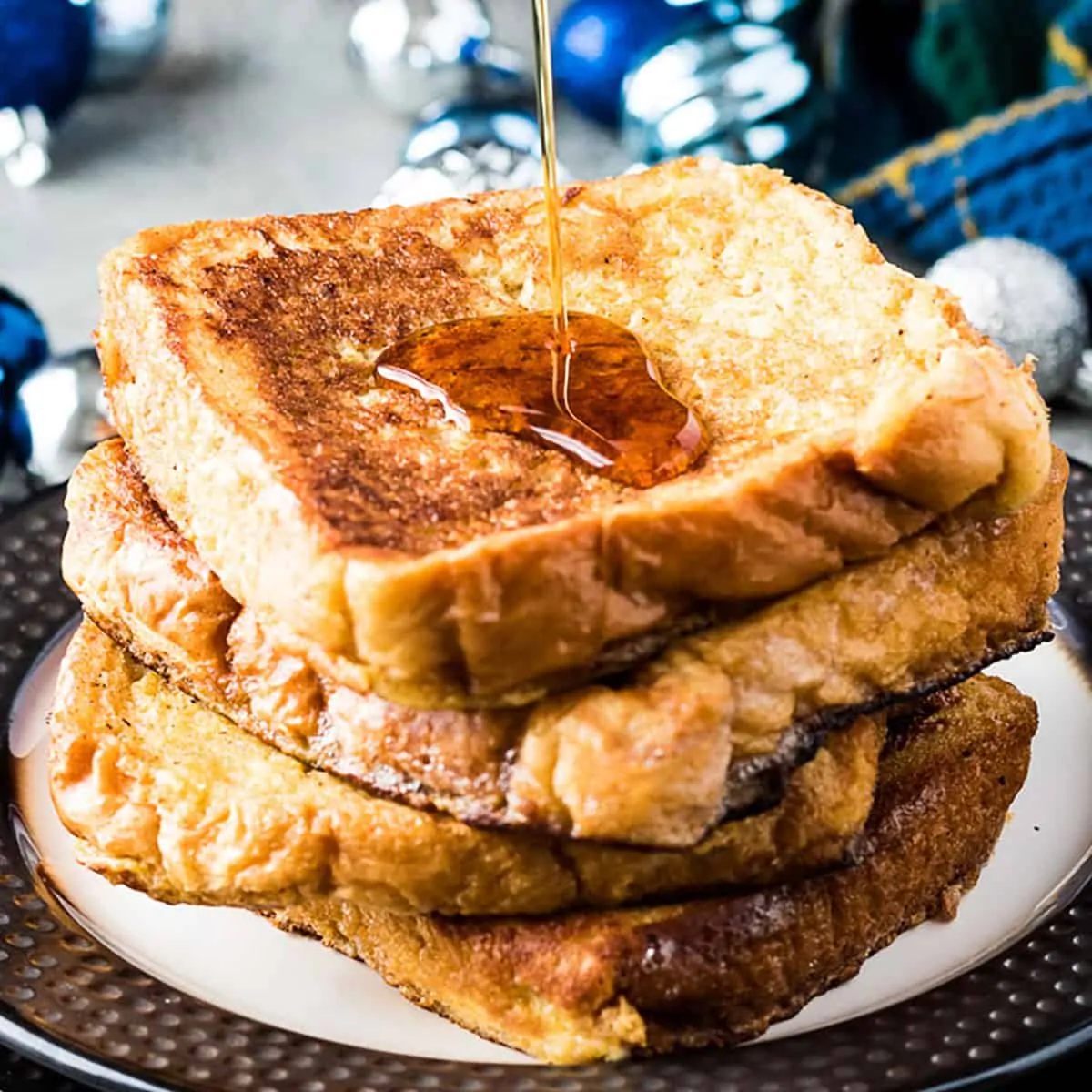 Stack of eggnog french toast being drizzled with syrup.