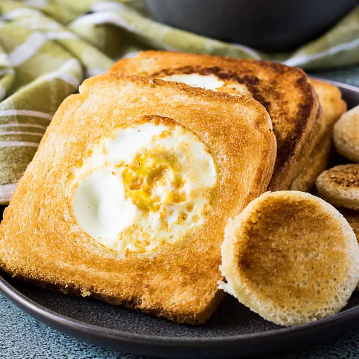 Eggs in a basket on a grey plate next to a green towel.