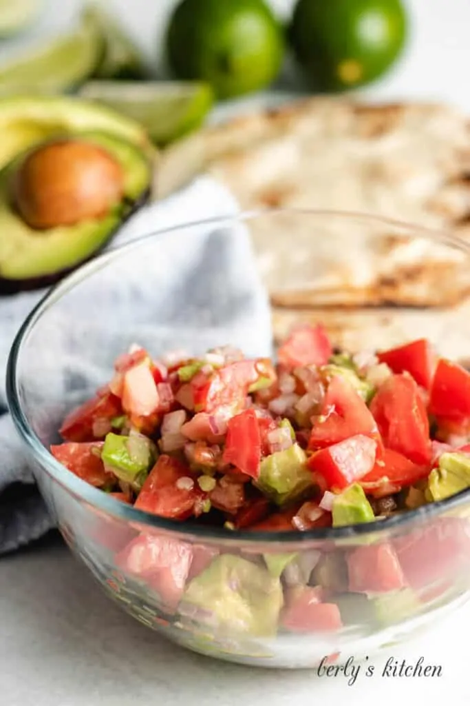 Tomatoes, avocados, and other veggies in a small bowl.