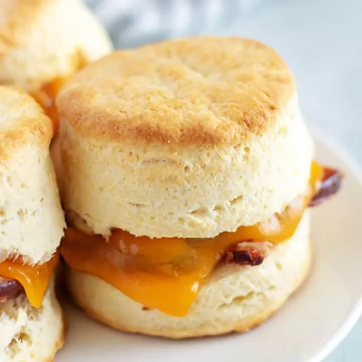 Ham biscuits with melted cheese on a white plate.