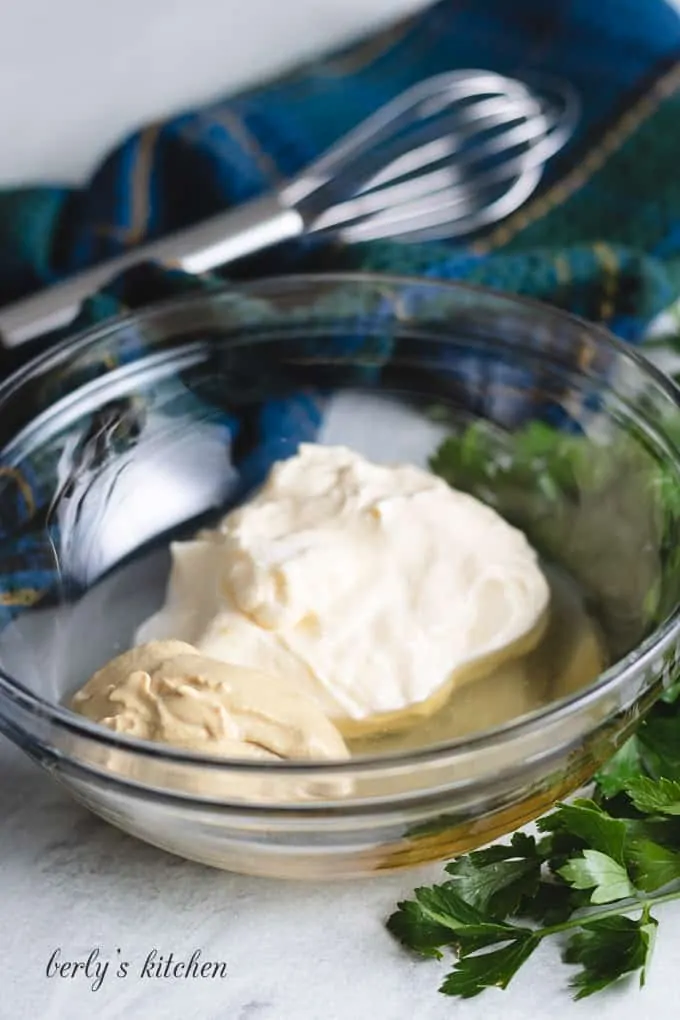 Mayonnaise, vinegar, and other ingredients in a mixing bowl.