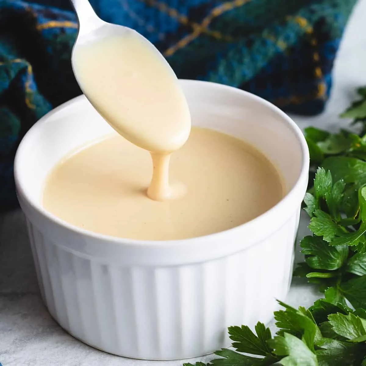 Honey mustard salad dressing being dipped from a ramekin.