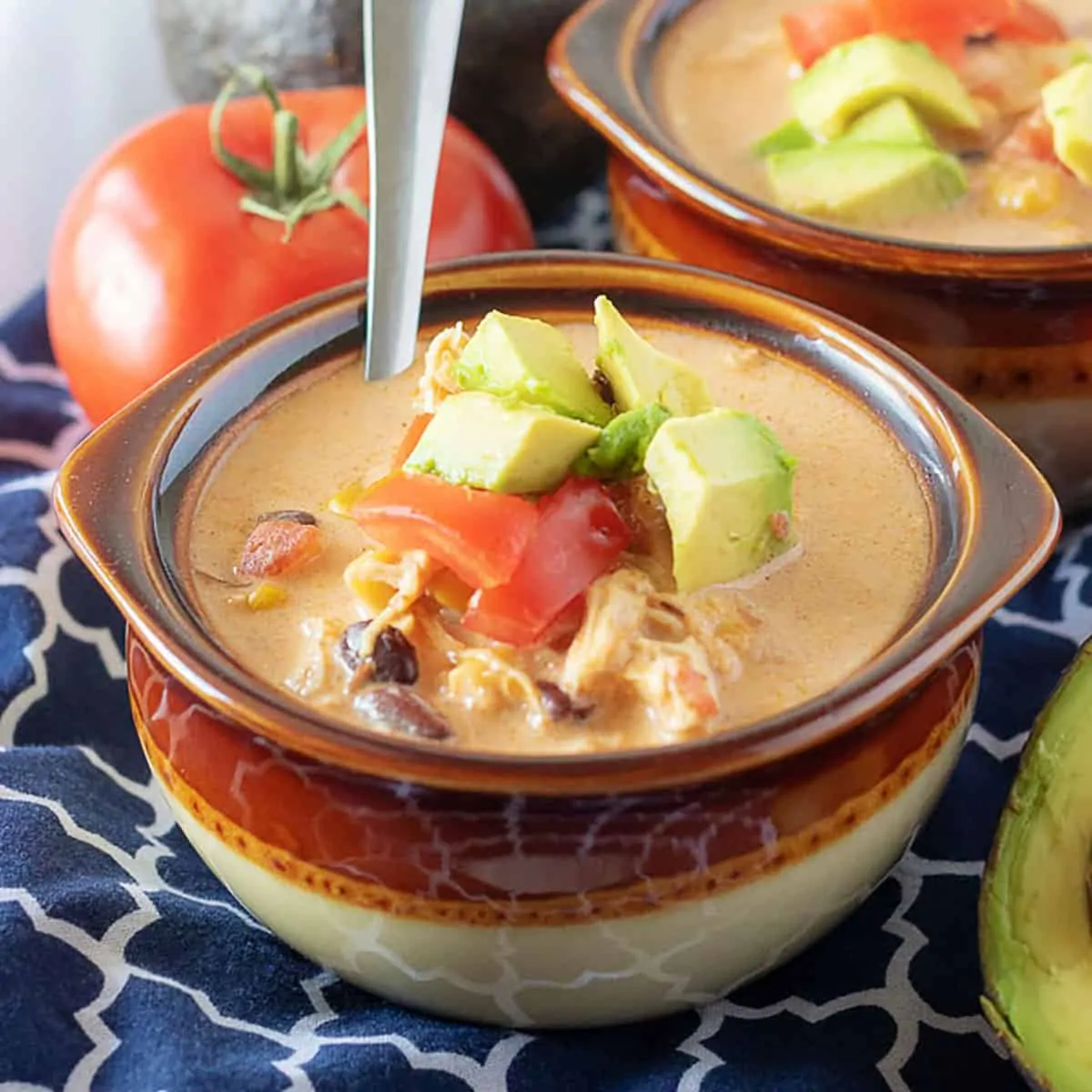 Bowl of instant pot chicken taco soup with tomatoes and fresh avocado.