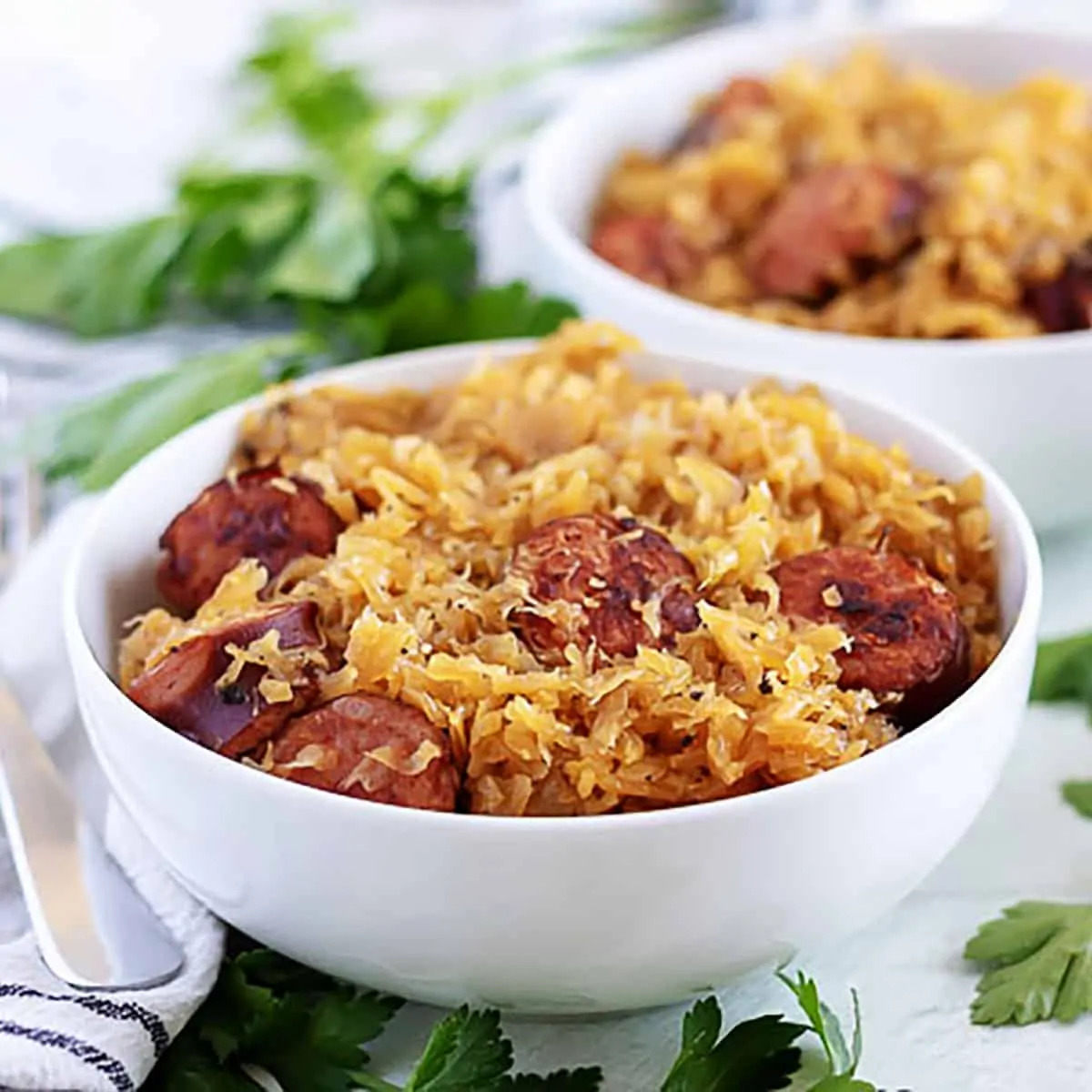 White bowl filled with sauerkraut and sauteed kielbasa sausage.