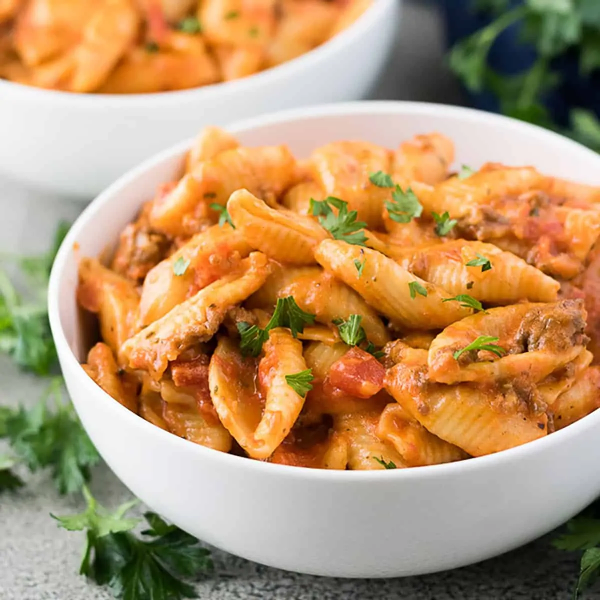 White bowl filled with cheesy shells and beef pasta.