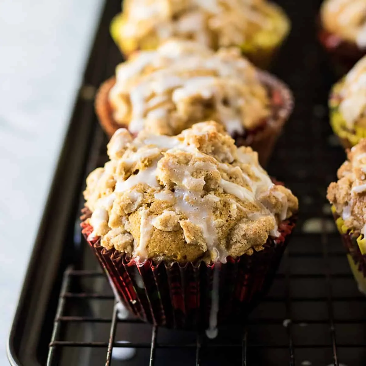 Pumpkin muffins on a wire rack covered with strussel and drizzle.