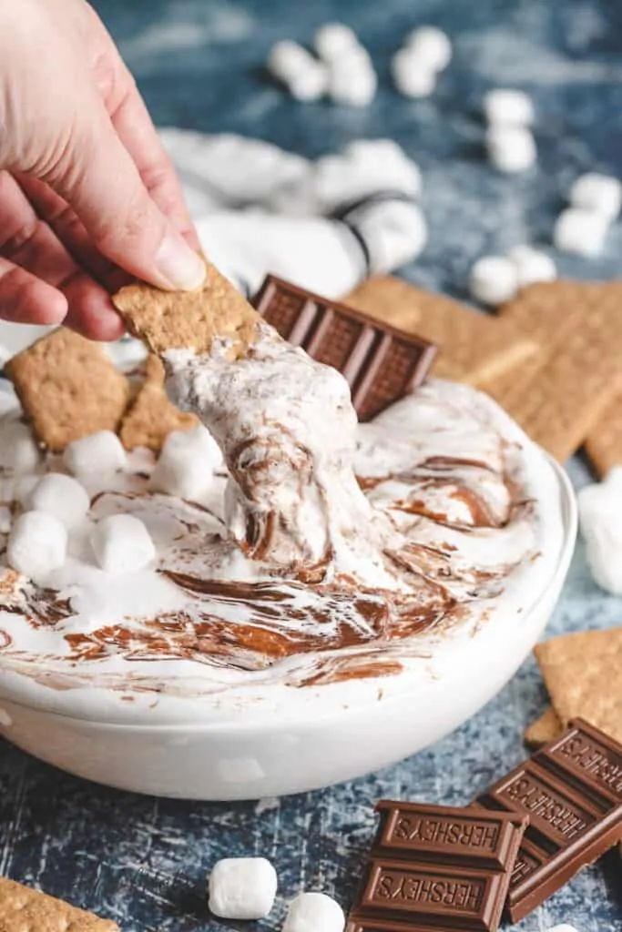 A graham cracker being dipped into the dessert dip.