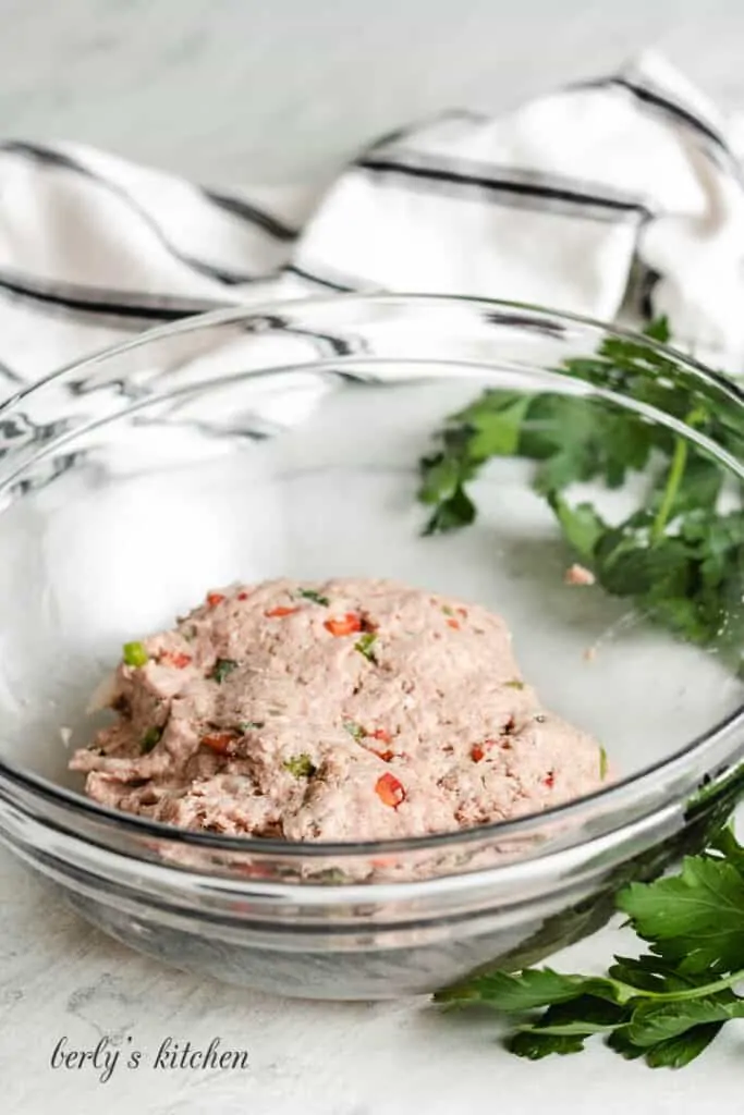 The raw poultry and other ingredients and mixed together in the bowl.