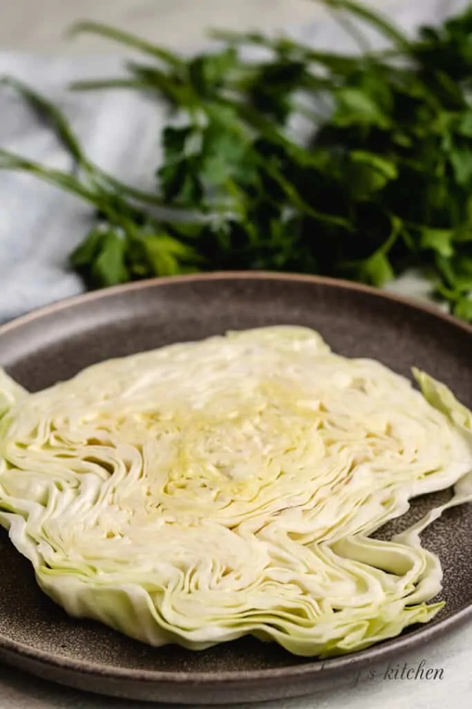 A 1-inch thick cabbage steak on a dark plate.