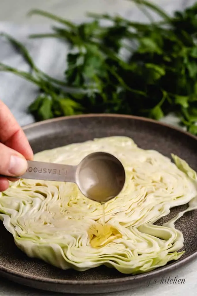 Oil being drizzled over the cabbage.