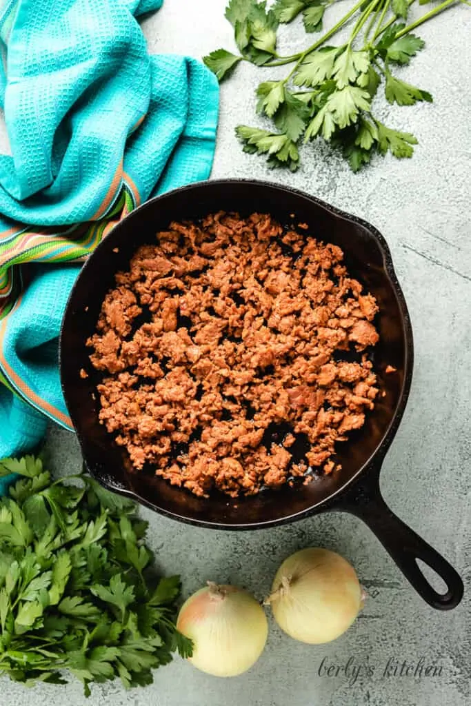 Chorizo sausage cooking in a cast iron skillet.