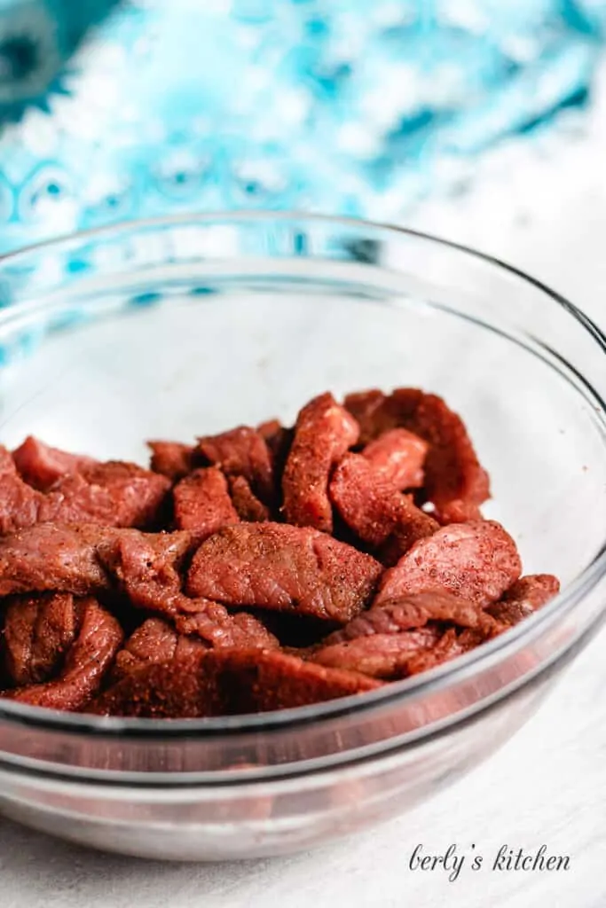 The spices and beef tossed together in a bowl.