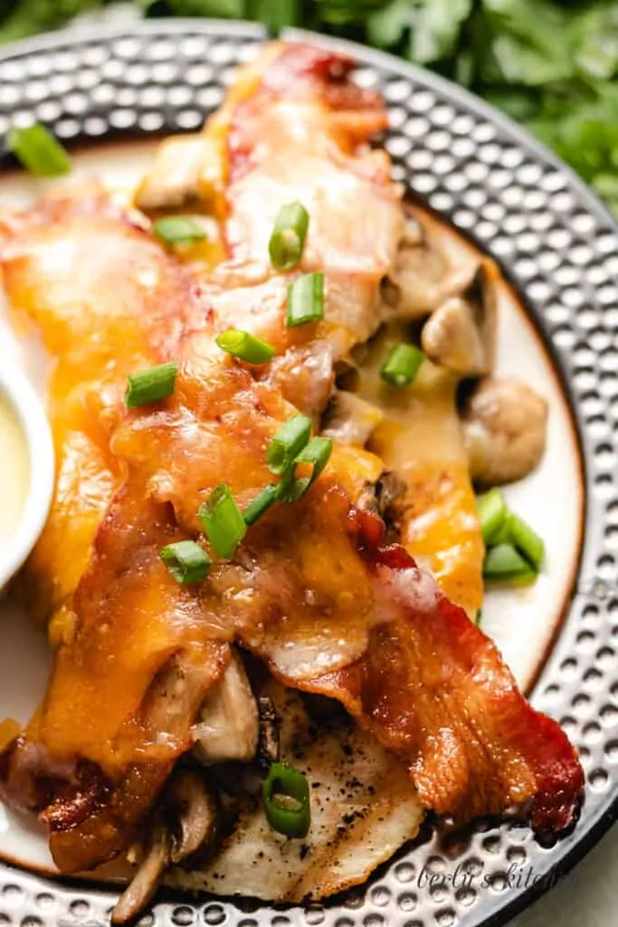 A close-up of the grilled chicken topped with cheese, and green onions.