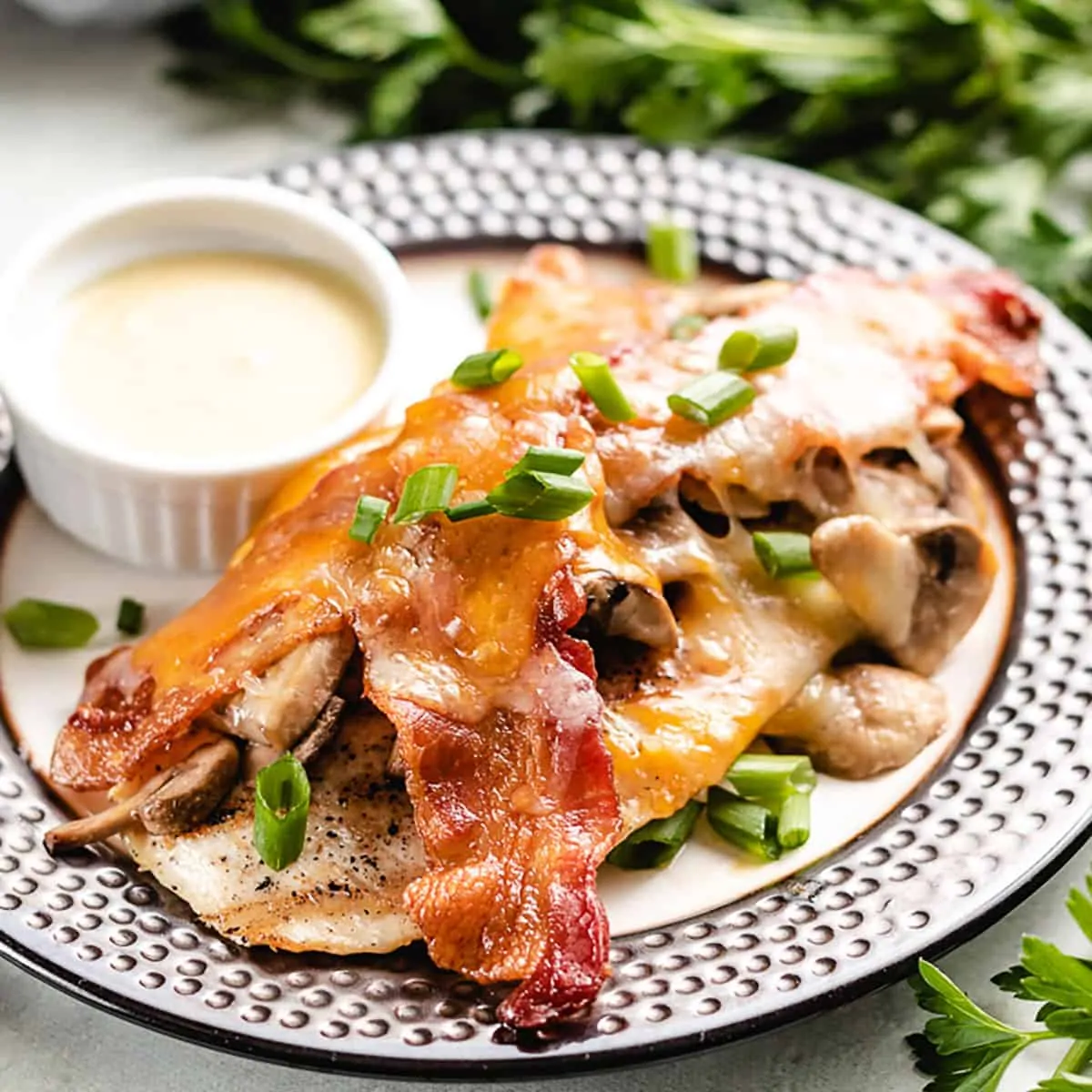 A chicken breast topped with cheese, mushrooms, and bacon.