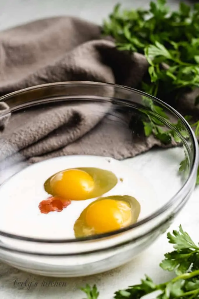 Eggs, milk, and hot sauce in a mixing bowl.