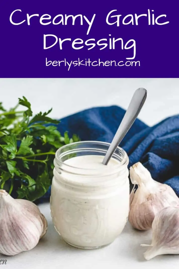 Creamy garlic dressing in jar with fresh garlic.