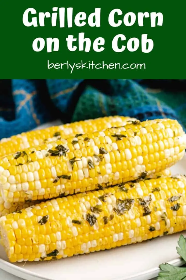 Seasoned and grilled corn on the cob served on a plate.