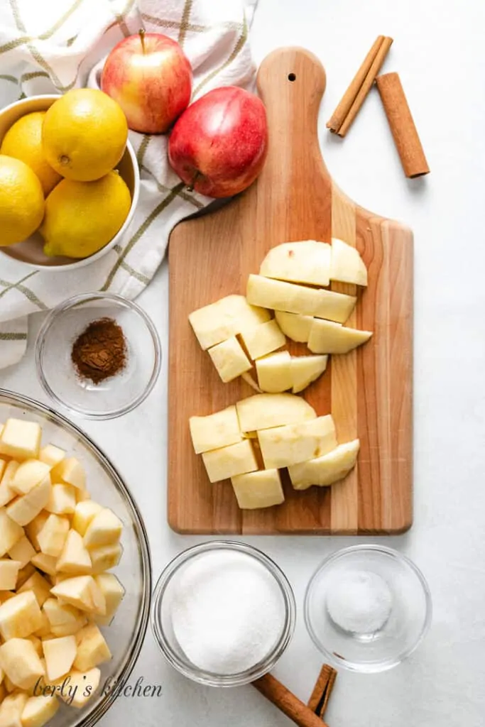 Diced apples on a cutting board surrounded by ingredients.