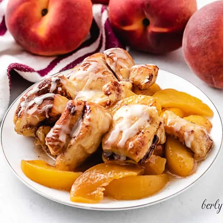 A serving of the cinnamon roll peach cobbler on a plate.