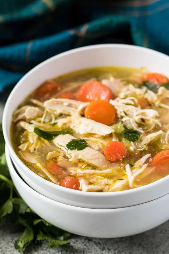 A bowl of chicken soup accented with a blue towel.