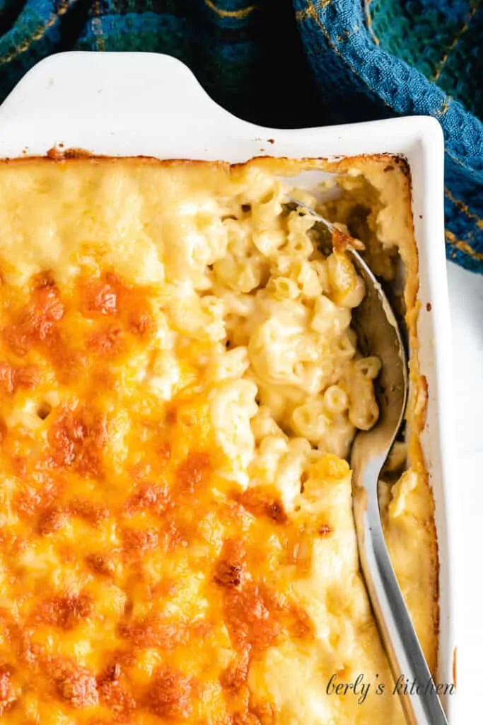 Mac and cheese being scooped from the baking dish.