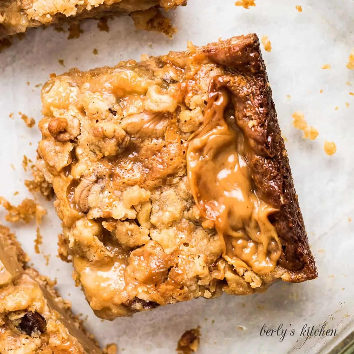 An apple crumble bar sitting on parchment paper.