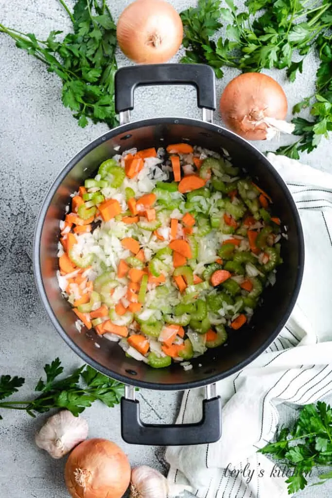 Carrots, and other ingredients cooking in a stock pot.