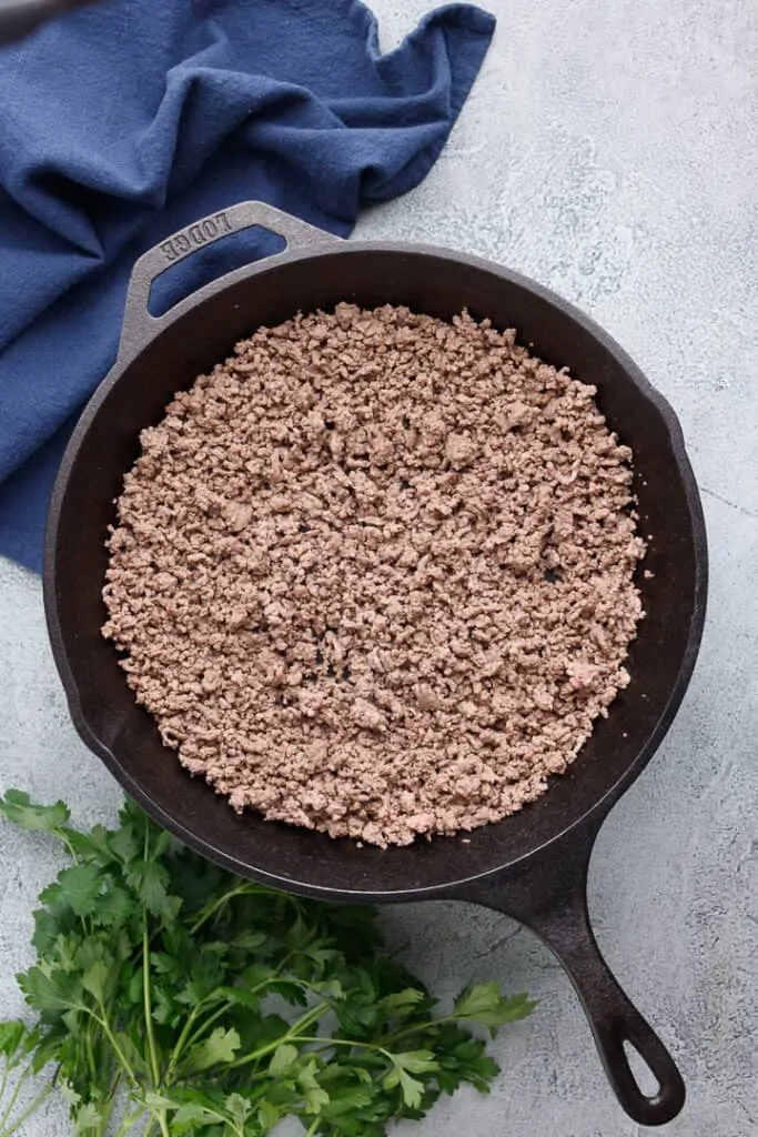 Ground beef cooking in a cast iron skillet.