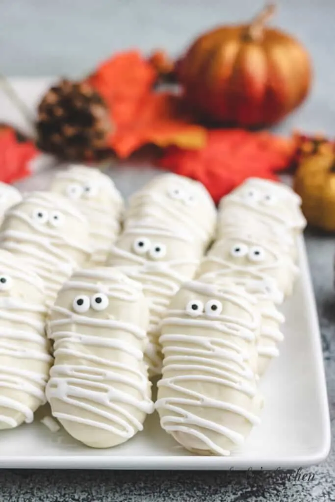 Nine mummy cookies on a plate.