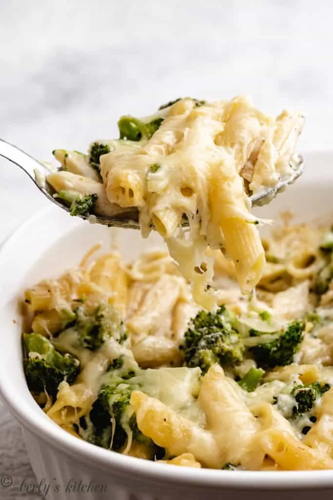 A scoop of the cheesy pasta being lifted from the casserole dish.