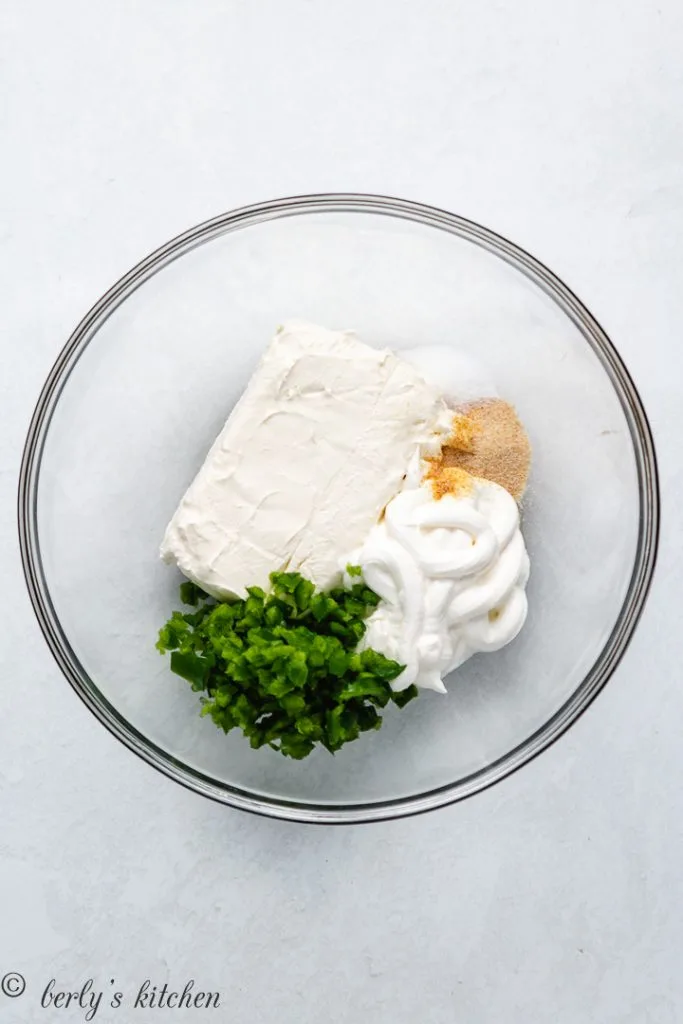 Cream cheese, sour cream, and other ingredients in a mixing bowl.