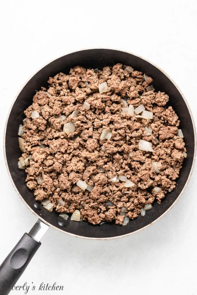 Ground beef and other ingredients cooking in a skillet.