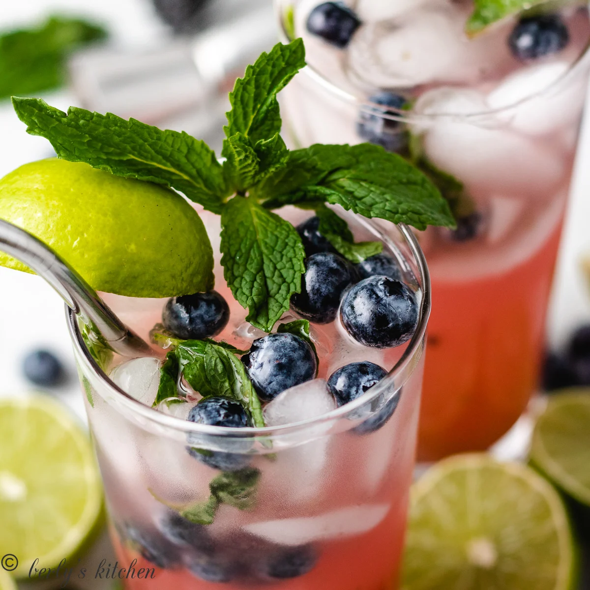 Two glasses of blueberry mojitos with fresh lime.