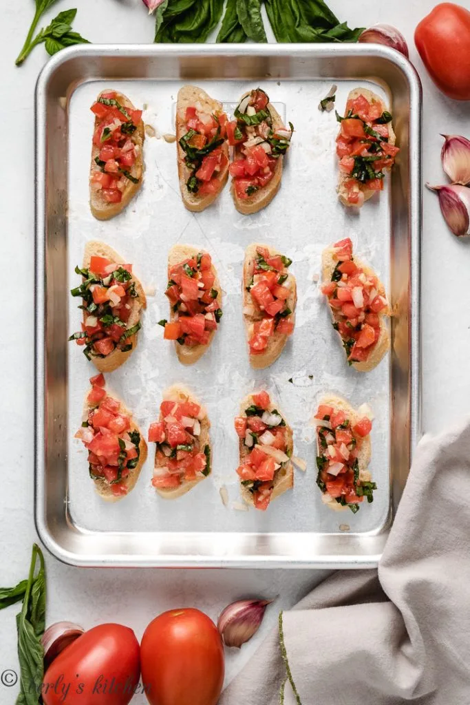 Top down photo of bruschetta on a baking sheet.